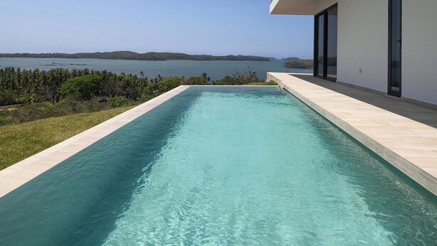 Una casa moderna con piscina que da a una extensa masa de agua.