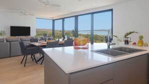 Una cocina moderna con una isla grande, comedor con vistas y sala de estar con televisor de pantalla plana.