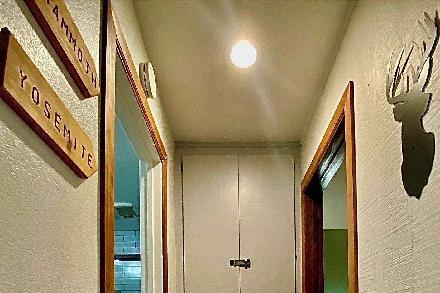 Ein Flur mit Namensschildern aus Holz, auf denen "PAMMOTH", "YOSHEMITE" und "YOSHEMITE" stehen. An der Wand ist eine Hirschskulptur angebracht.