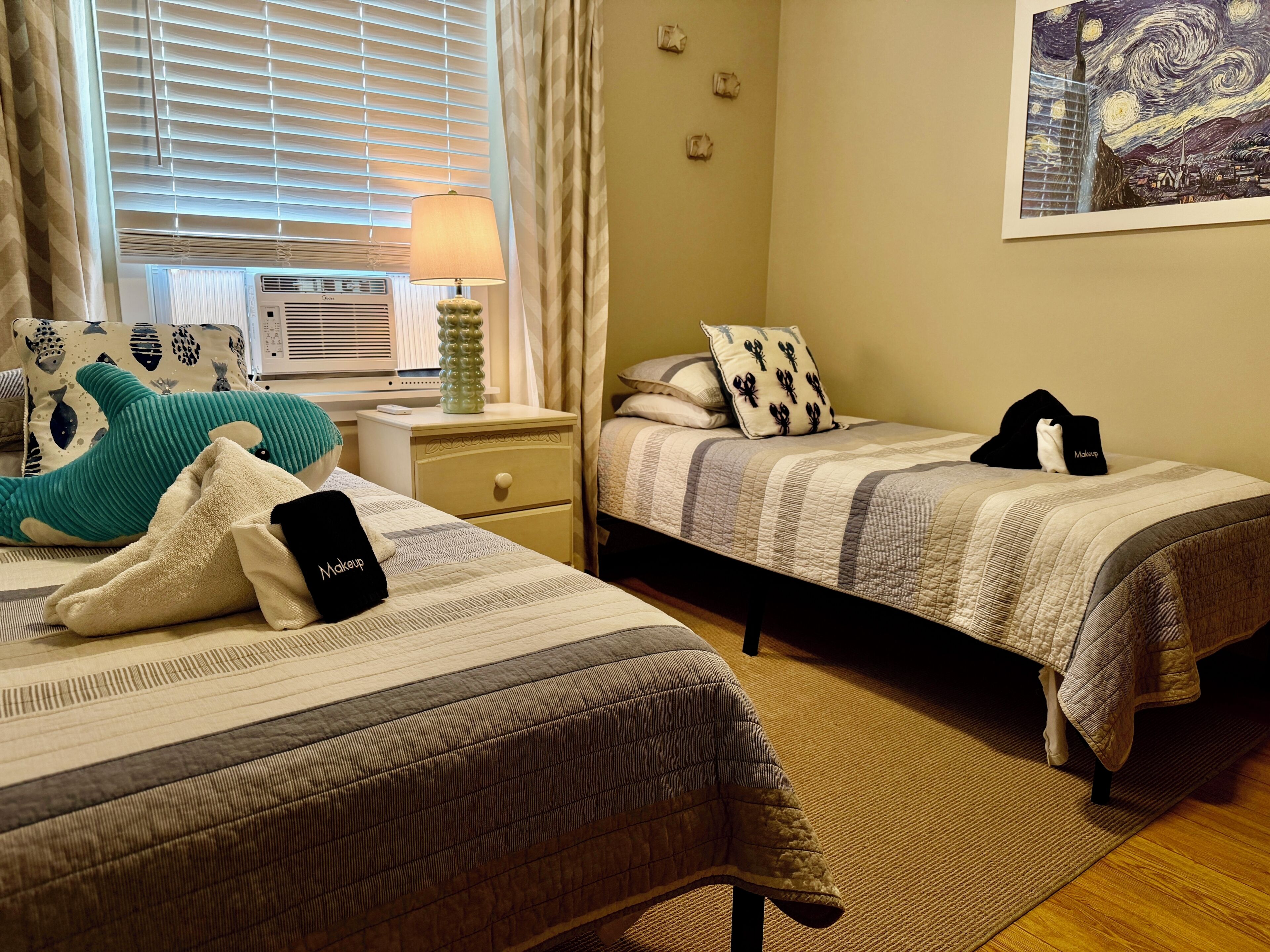 A bedroom with two beds, a nightstand, a lamp, and a painting on the wall.