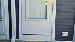 A front door with a number '1' above it, a doormat with 'hello' written on it, and a small wall-mounted light fixture to the right.
