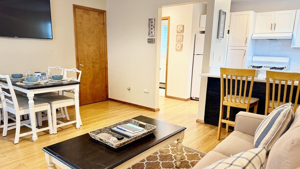 A living room with a sofa, a coffee table, and a dining area with a table and chairs.