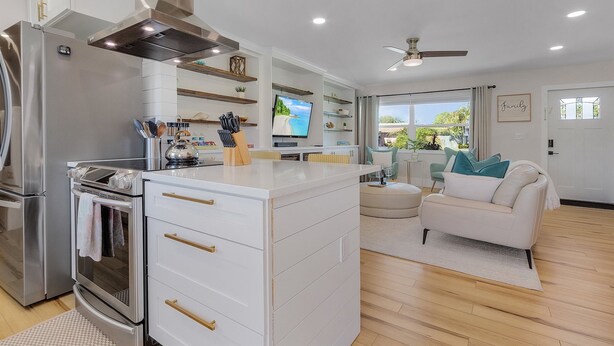 A modern kitchen with stainless steel appliances, a central island, and a dining area with a view.