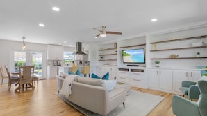 A modern living room with a sofa, TV, and dining area.