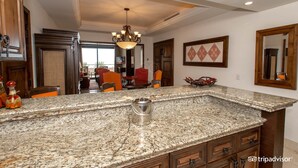 A kitchen with granite countertops, wooden cabinets, and a chandelier.