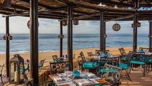 An outdoor dining area with tables and chairs, overlooking the ocean.