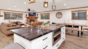 A modern kitchen with a marble island, white cabinetry, and a stone fireplace. - Elmwood Place #2218 (Big Bear City)