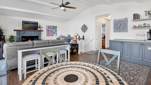 A living room with a fireplace, a sofa, a coffee table, and a dining area with chairs. - North Shore Chalet #2173 (Fawnskin)