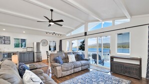 A spacious living room with a large gray sectional sofa, a ceiling fan, and a view of a lake through large sliding glass doors. - North Shore Chalet #2173 (Fawnskin)