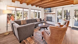 A cozy living room with a sectional sofa, a leather armchair, a fireplace, and large windows. - Splash Mountain #1904 (Big Bear Lake)