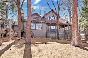 A two-story house with a covered porch, a fenced yard, and a view of the surrounding trees.