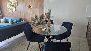 Un soggiorno moderno con un tavolo da pranzo in vetro, sedie blu scuro, un divano blu e opere decorative alle pareti.