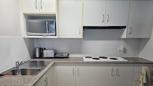 Una cucina con piano di lavoro in granito, lavello in acciaio inossidabile, microonde, tostapane e piano cottura a gas.