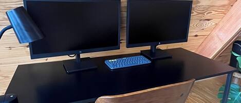 A wooden desk with two monitors, a keyboard, and a mouse.