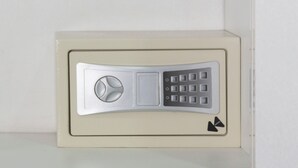A beige safe with a combination dial and keypad, located in a corner against a white wall. - Casa Ramos Salamanca (Lima)