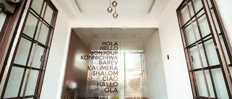 A hotel entrance with a glass door and a sign displaying greetings in multiple languages.
