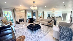 A spacious living room with a fireplace, a piano, and a modern chandelier. - Relax with whole family at peaceful place and enjoy easy access to everything. (Redondo Beach)