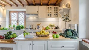 A kitchen with white cabinets, a wooden ceiling, and a variety of fruits and vegetables on the counter. - Grumo Farmhouse in Pescaglia (Pescaglia)