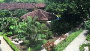 A courtyard with a tiled-roof building, surrounded by lush greenery and a well-maintained garden. - Beach Area Studio (Playas del Coco)