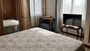 Una camera d'albergo con un letto, una scrivania, un televisore e un armadio.