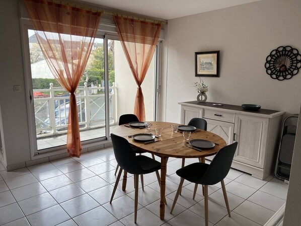 Un coin repas avec une table ronde, des chaises noires et un buffet blanc.