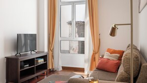 A living room with a sofa, a flat-screen TV on a wooden stand, a glass coffee table, and a wine glass. - In the centre of Funchal - Apartamento do Carmo I (Funchal)