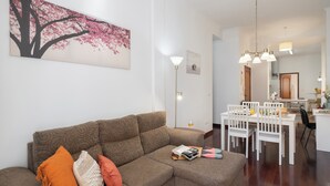 A modern living room with a sectional sofa, a dining area with a white table and chairs, and a kitchen in the background. - In the centre of Funchal - Apartamento do Carmo I (Funchal)