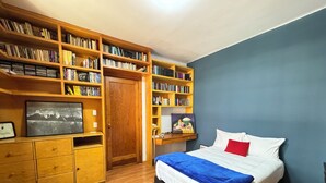 Un dormitorio con una cama, estanterías de madera, un escritorio y un televisor.