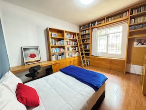A bedroom with a bed, a desk, a chair, a bookshelf, and a window. - Casa Alquimia Condesa (Mexico City)