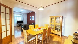 Un comedor con una mesa y sillas de madera, un aparador con puertas de cristal y un televisor al fondo.