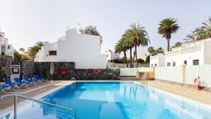 A swimming pool with clear blue water, surrounded by white buildings and palm trees. - Home2Book Charming Apt Costa Adeje, Pool&Terrace (Playa de las Americas)