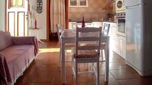 Una cocina acogedora con vigas de madera, una mesa de comedor con sillas, un refrigerador y un sofá en la sala.