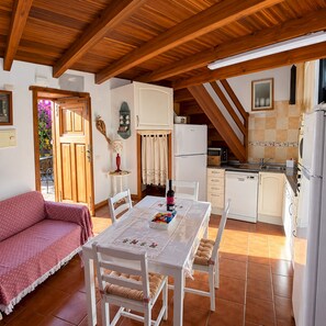 A cozy kitchen with a dining table, chairs, and a refrigerator.