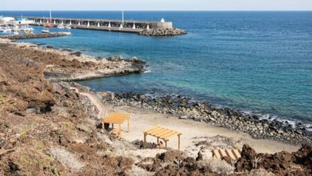 A coastal area with rocky terrain, a wooden bench, and a pier with boats. - Charming Apartment & Diving La Restinga (La Restinga)
