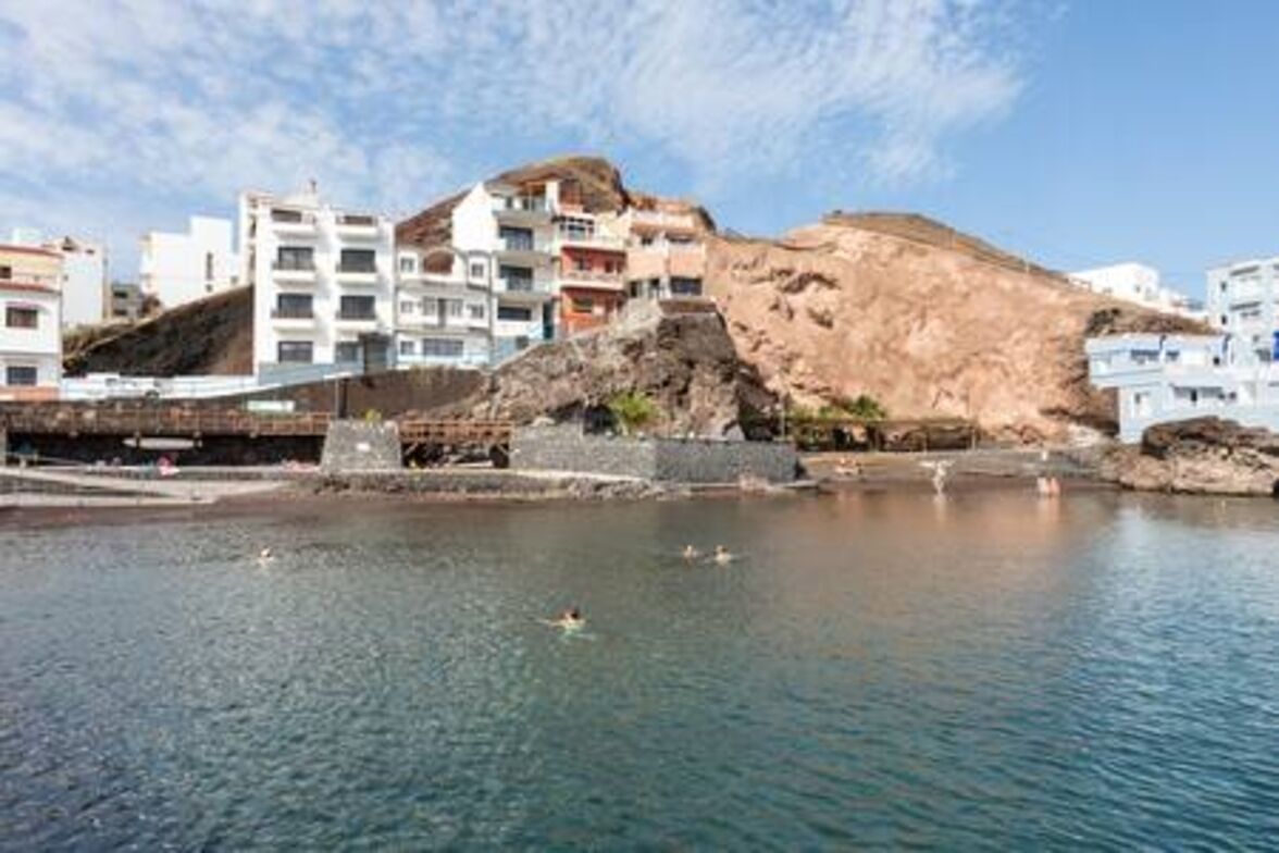 A coastal town with buildings on a hillside overlooking a calm sea.