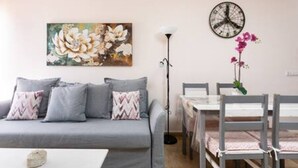 A living room with a grey sofa, a painting, a clock, and a vase with flowers. - Charming Apartment & Diving La Restinga (La Restinga)