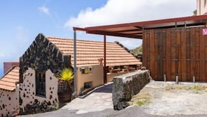 A building with a tiled roof, a stone wall, and a wooden door. - La Pestilla 3 - Cozy rustic house, El Hierro (Taibique)