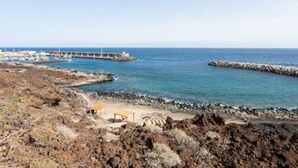 A coastal landscape with rocky terrain, a pier extending into the sea, and a sandy beach area. - La Pestilla 3 - Cozy rustic house, El Hierro (Taibique)