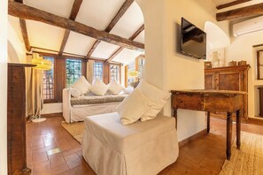 A room with a bed, a table, a TV, and a wooden ceiling.
