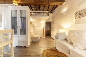 A cozy interior with a white sofa, a wooden floor, a cabinet with glass doors, and a lamp.