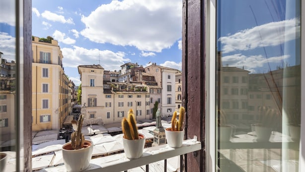 Un balcón con cactus en macetas y vistas a edificios históricos.