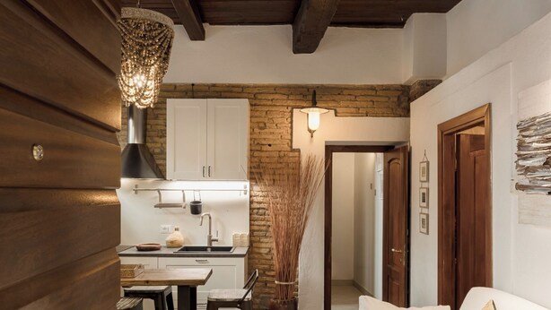 Une cuisine de taille réduite avec un plafond en bois, un plan de travail blanc et un luminaire suspendu.