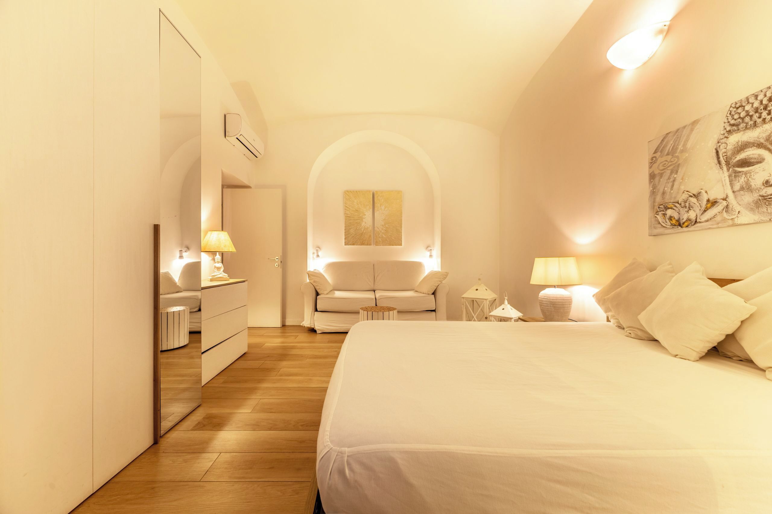 Ein Schlafzimmer mit einem großen Bett, einem Sofa, einem Spiegel und einem Bild an der Wand.