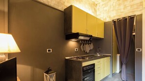 A compact kitchen with a gas stove, oven, and yellow cabinets. - SPLENDID APARTMENT TRASTEVERE (Roma)
