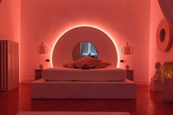 A modern bedroom with a circular skylight, a bed, and two bedside tables.