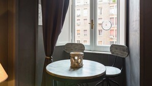 A corner room with a window, a table with a candle, and two chairs. - SPLENDID APARTMENT TRASTEVERE (Roma)
