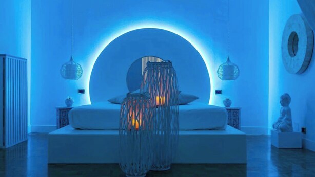 A modern room with a white sofa, two hanging lamps, and a circular light fixture above the sofa. - SPLENDID APARTMENT TRASTEVERE (Roma)