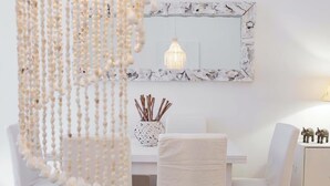 A room with a white dining table, two chairs, a hanging light fixture, a decorative mirror, and a small cabinet with figurines. - SPLENDID APARTMENT TRASTEVERE (Roma)