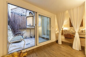 Un salon moderne doté d’une porte-fenêtre coulissante donnant sur un balcon, d’un canapé, d’une table basse et d’une sculpture décorative.