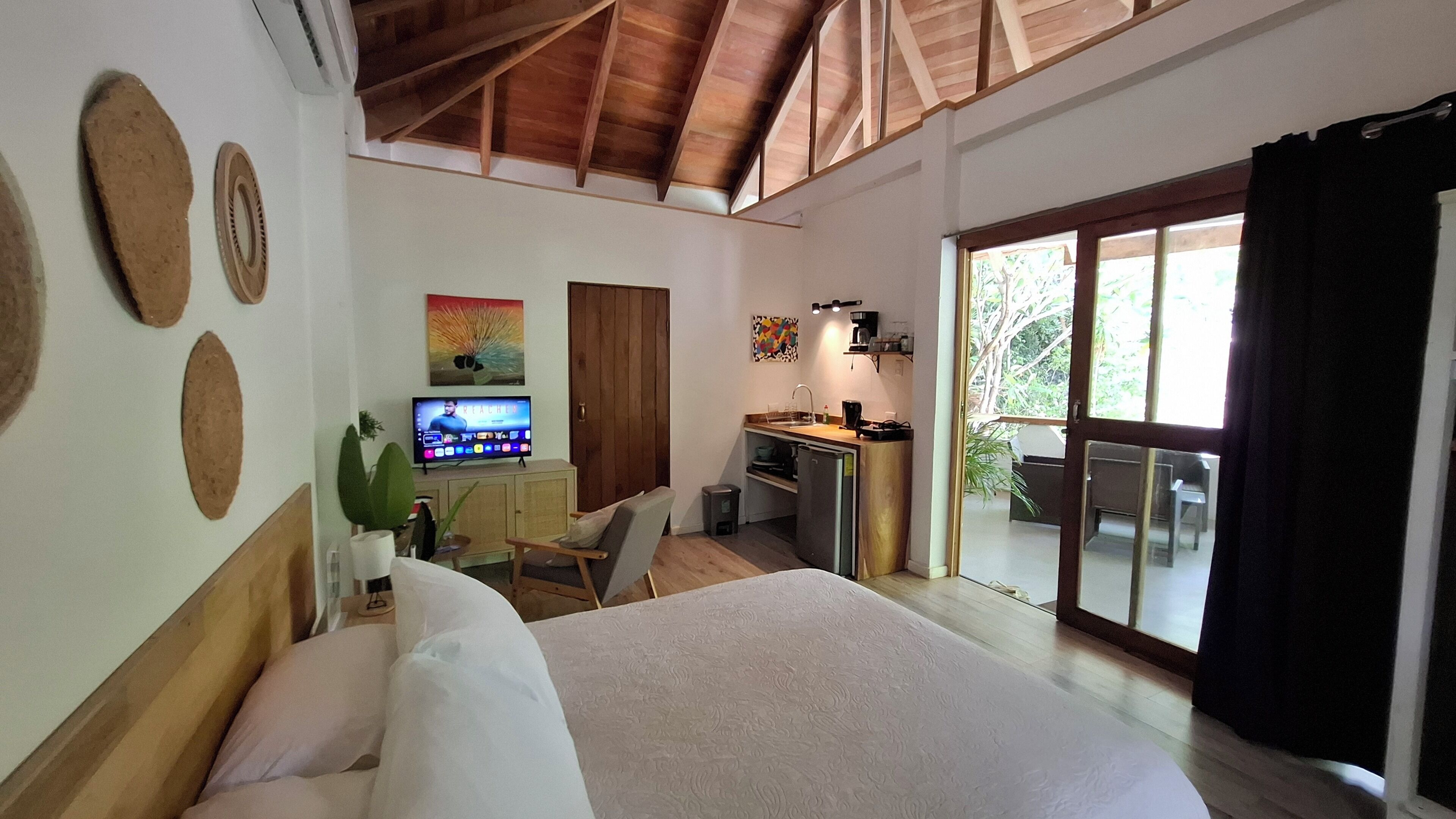 Ein Schlafzimmer mit Bett, Fernseher, Schreibtisch und einem Balkon mit Blick.